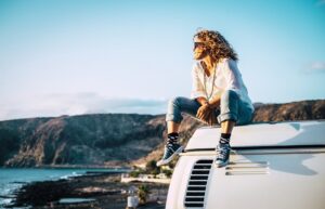 Travel concept with independent people enjoyig the outdoor leisure activity and wanderlust life lifestyle - woman sit down on the roof of a old nice vintage camper van